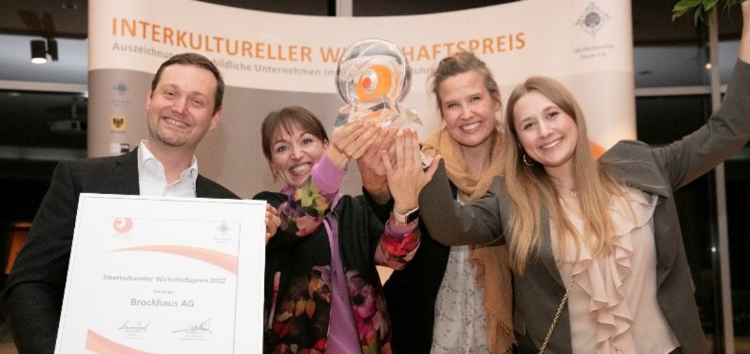 Vier Personen halten eine Urkunde und die Trophäe des IWP in die Höhe.