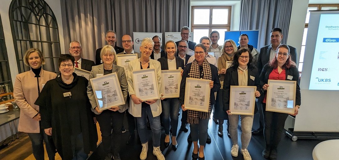 Das Bild zeigt die ausgezeichneten Unternehmen die stolz ihre Urkunden in die Kamera halten.