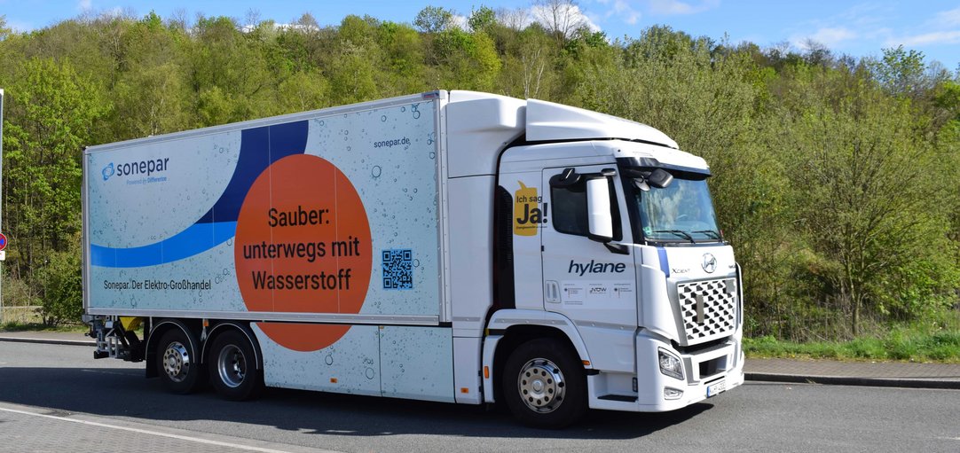 LKW auf Straße. Aufdruck: "Sauber: unterwegs mit Wasserstoff"