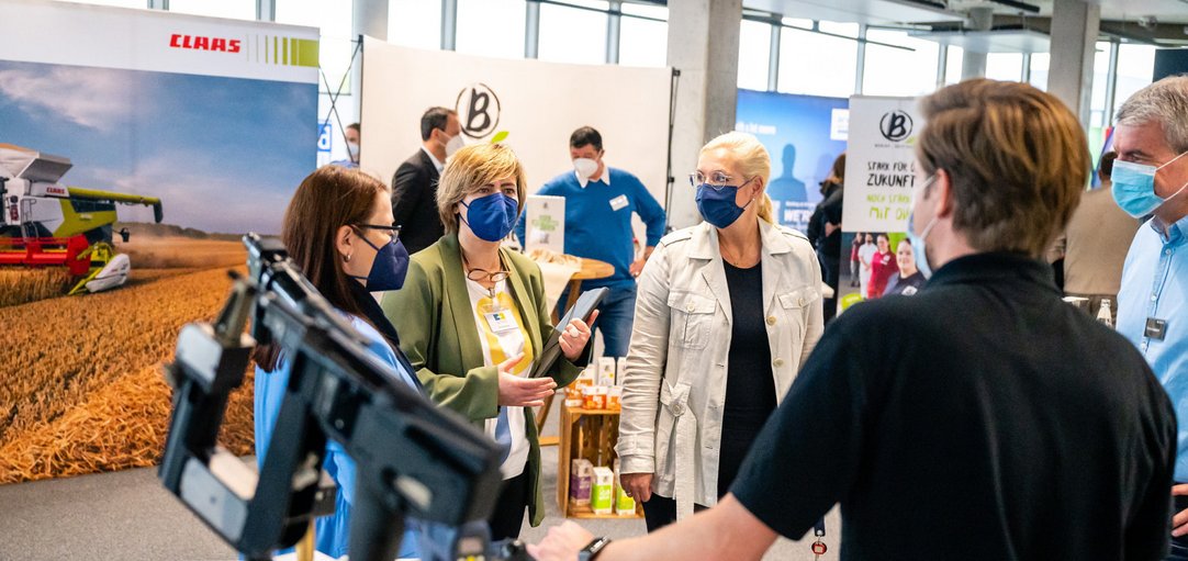 Das Bild zeigt Studierende, die sich an einem Messestand informieren.