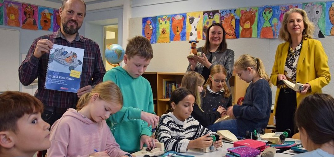 Das Bild zeigt Grundschülerinnen und Grundschüler, die einen Fleckiflitzer bauen. 