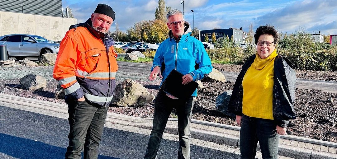 Das Bild zeigt zwei Männer und eine Frau, die sich die neue Straße anschauen. 