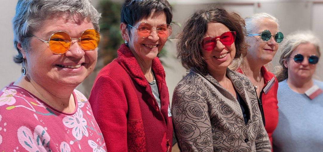 Das Bild zeigt vier Frauen, die Brillen mit bunten Gläsern tragen.