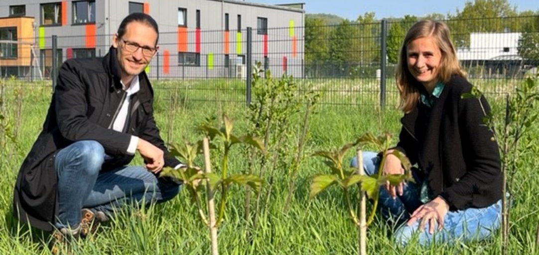 Sascha Dorday und Nora Scherz auf einer Wiese neben den frisch gepflanzten Sträuchern und Bäumen.