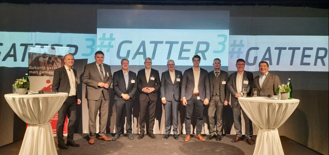 Eine Gruppe von Männern vor dem # Gatter 3 Logo.