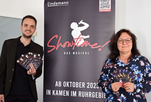 Gründer und Gründungsberaterin vor dem Roll-up des Musicals "Showtime!"